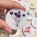 Macro detail of round phone grip featuring real purple dried flowers and glitter in resin - Purple Baby's Breath