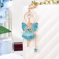 Detail of blue rhinestone flower fairy keychain with gold finish on a quilted bag - Blue