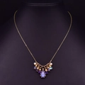 Collar dorado con gema azul en forma de pera y perlas de agua dulce sobre fondo negro - Collar de Colgante Fijo de Amatista y Perla