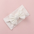 Close-up of white knitted baby headband with a large bow on a soft pink background - White
