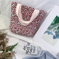 Dettaglio della borsa tote a pois marroni con manico in tela rosa su letto bianco - Stile a pois marrone rossastro (punti rossi e verdi)