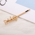 Pasador de pelo dorado con letras Friday en aleación metálica brillante sobre tela blanca - Viernes