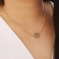 Primer plano de collar estrella de oro rosa con incrustación oscura en una modelo - Gris