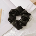 Glossy black satin scrunchie hair tie with elegant silk texture on a magazine - Black