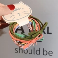 Detail view of colorful bow-style elastic hair ties in cat-shaped packaging - Multicolor