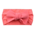 Soft nylon baby headband with a large coral pink knotted bow on a plain white background - Watermelon Red