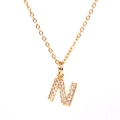 Macro shot of gold letter N pendant with micro-pave crystal inlay and fine gold chain - Letter N