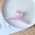 Detailed view of large matte pink hair claw clip placed on a decorative white tray - Crossed / Purple