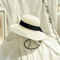 Detail of a woven straw hat with a wide black ribbon bow on a minimal display stand - Cream White (Adult)