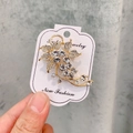 Élégante broche tulipe dorée avec cristaux blancs et perles sur une carte - A7-39