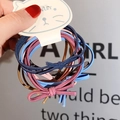 Close-up of colorful bow hair ties on cat-shaped card holder held by a hand - Morandi Color