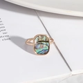 Detailopname van rechthoekige abalone schelp inleg op een roségouden ring met textuur - Abaloneschelp