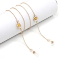 Golden daisy pendant eyewear chain with non-slip silicone loops on a white stand - Daisy / Gold