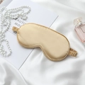 Luxurious champagne gold silk sleep mask with elastic strap on white velvet background - Gold Eye Mask