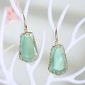 Primer plano de pendientes geométricos de cristal verde claro con ganchos de metal dorado - Verde