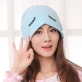 Light blue knit postpartum hat with eyelash embroidery on a female model - Smiley / Blue