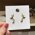 Elegante gouden vlinder oorbellen met kristallen op een witte sieraden display kaart - Gouden vlinder oorbellen