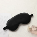 Luxurious black silk sleep mask with elastic headband on a cozy lifestyle background - Black