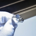 Close-up of elegant moissanite ring with twisted band held by white gloved fingers - Adjustable Open / Twisted Shank Three-Stone Gem Style (10)