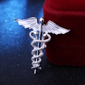 Dettaglio spilla caduceo in argento con ali in smalto bianco su velluto rosso - Argento