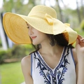 Detalle de un sombrero de sol de paja amarilla con ala ancha y lazo decorativo grande - Amarillo