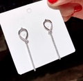 Close-up of silver long geometric earrings with sparkling rhinestones on a card - Silver