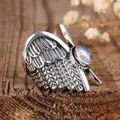 Vintage silver angel wing ring with round moonstone on a rustic wood background - US 7