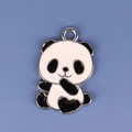 Detalle macro de un dije de panda en esmalte blanco y negro con lazo plateado en fondo azul - Panda 2