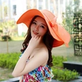 Detail of a bright orange wide-brim straw hat featuring an elegant side bow decoration - M (56-58cm) / Orange