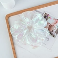 Macro shot of iridescent white organza scrunchie on marble tray with elegant pearl luster - White