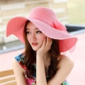Detail of pink wide-brimmed straw hat featuring a matching silk bow for sun protection - M (56-58cm) / Pink