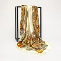 Detail of silk satin scarf with orange paisley print hanging on a black metal stand - Beige