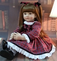 Detail of 60cm reborn doll in red plaid dress featuring realistic brown hair with bows - 55cm Full Silicone