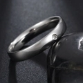 Polished stainless steel ring with a round zircon stone on a black pebble background - US 6 / Steel