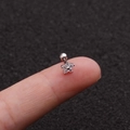 Petite silver flower cartilage stud with cubic zirconia stones shown on a fingertip - Silver