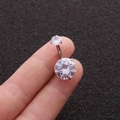 Close-up of polished silver stainless steel belly ring with sparkling round cubic zirconia - White