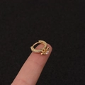 Makroaufnahme goldener Huggie-Ohrring mit funkelndem Zirkon-Flügelanhänger Detail - Silber / Flügel