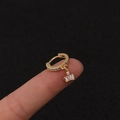 Detail eines goldenen Creolen-Ohrrings mit Kronenanhänger und rechteckigem Zirkoniastein - Silber / Krone