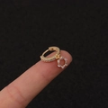 Makroaufnahme eines vergoldeten Blitz-Ohrrings mit Zirkonia auf den Fingerspitzen - Silber / Sechseck