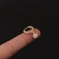 Makroansicht goldene Creolen mit Sternenanhänger und Zirkonia-Besatz auf dem Finger - Silber / Achtzackiger Stern