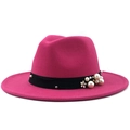 Detail eines rosafarbenen Fedora-Hutes mit weißen Perlen, Nieten und einer Metallblume - Fuchsia