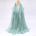 Detail of mint green sun protection scarf with lightweight pleated texture hanging on a stand - Bean Green