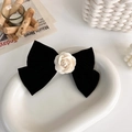Détail d'une pince à cheveux en velours noir avec camélia blanc sur un plateau - Noeud de Camélia en Velours Noir