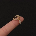 Makroaufnahme der goldenen Creolen mit Kristall-Blattanhänger auf der Fingerspitze - Silber / Blatt