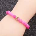 Pink ice crack beaded bracelet with golden crown charm shown on a model wrist - Pink Distressed Gold Crown (Distressed A)