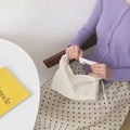 Minimalist off-white baguette bag with pleated handle shown in a fresh lifestyle setting - Cream
