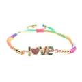 Makroaufnahme von buntem geflochtenem Armband mit goldenem LOVE-Anhänger und CZ - Mehrfarbiges geflochtenes Seil
