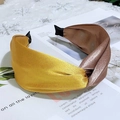 Detalle de diadema ancha de satén con nudo retorcido bicolor sobre página de revista - Amarillo + Malva