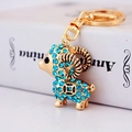 Golden ram keychain with blue crystals and lucky coin charm on elegant white book - Blue Little Sheep
