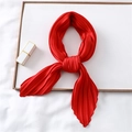 Close-up of bright red pleated silk scarf with accordion texture in a white tray - Red
